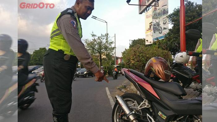 ilustrasi-polisi-menunjukkan-pelanggaran-berupa-pemakaian-knalpot-tidak-sesuai-standar.jpg