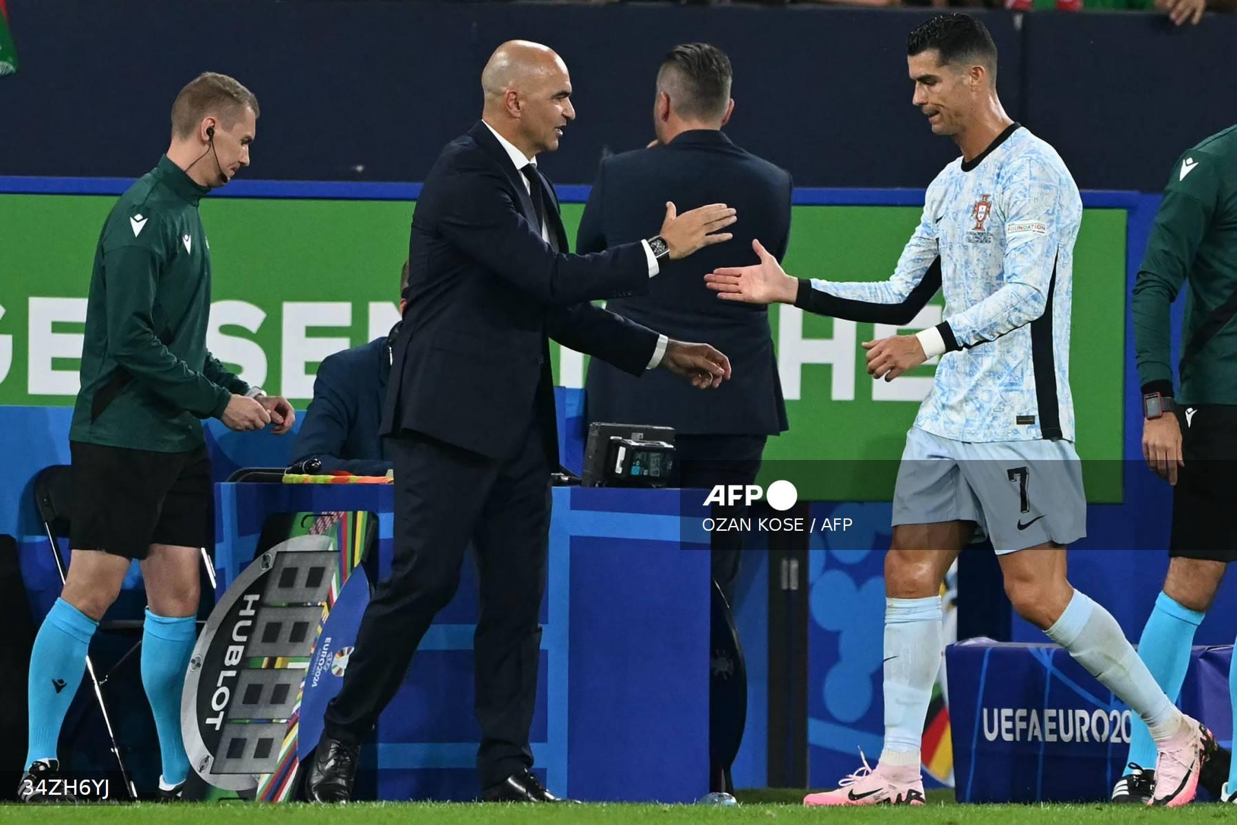 Pelatih kepala Portugal Roberto Martinez berjabat tangan dengan penyerang Portugal #07 Cristiano Ronaldo saat ia meninggalkan lapangan untuk diganti selama pertandingan sepak bola Grup F UEFA Euro 2024 antara Georgia dan Portugal di Arena AufSchalke di Gelsenkirchen pada 26 Juni 2024.