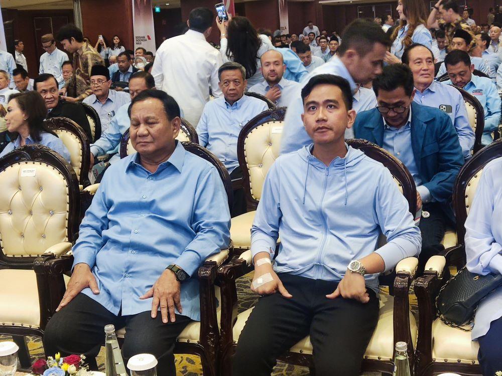 Wakil Presiden Gibran Rakabuming Raka melambaikan tangan sambil menuruni tangga pesawat kepresidenan di landasan bandara, dikelilingi oleh staf dan pengamanan. Suasana pagi hari dengan latar belakang pesawat besar.