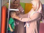 Dua-fasilitator-tersenyum-saat-mengukur-tinggi-badan-anak.jpg<pf>Kesederhanaan-bagian-depan-bangunan-Rumah-Anak-SIGAP-Sokawera.jpg<pf>Anak-mencocokkan-warna-sedotan-saat-kelas-bermain-bersama-di-Rumah-Anak-SIGAP-Sokawera.jpg<pf>Fasilitator-Rumah-Anak-Sigap-Sokawera-memberikan-materi-mencocokkan-angka-dan-warna.jpg<pf>Anak-peserta-kelas-bermain-bersama-mencocokkan-warna-didampingi-ibunya.jpg<pf>Landscape-sekitar-bangunan-Rumah-Anak-SIGAP-Sokawera.jpg<pf>Anak-peserta-kelas-bermain-bersama-melambai