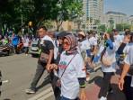 Buruh Pakai Kaos Bergambar Orang Mengepal Tangan dengan Tulisan 