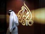 Seorang-pria-berjalan-di-belakang-logo-kantor-berita-asal-Qatar-Al-Jazeera.jpg