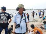 darwin-juru-foto-di-sela-sela-kerjanya-menawarkan-jasa-foto-ke-pengunjung-pantai-ancol.jpg