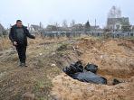 seorang-pria-menunjuk-kuburan-massal-di-kota-bucha-ukraina-pada-3-april-2022.jpg
