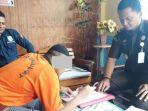 tampak-tersangka-ms-alias-sd-50-mengenakan-kaus-warna-orange-menanda-tangan.jpg