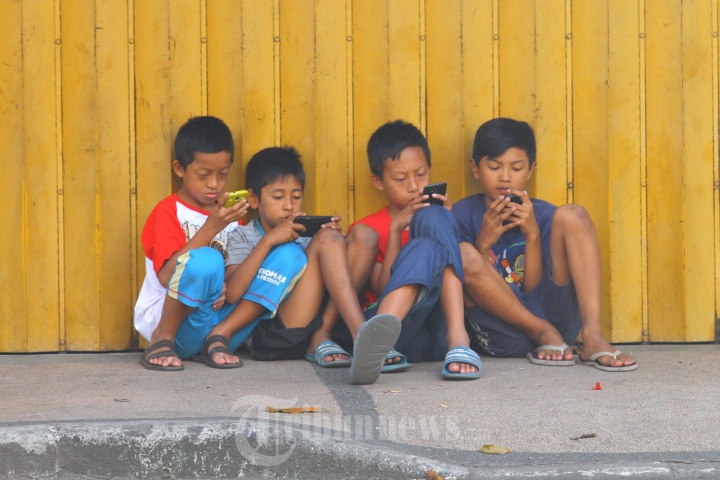 Anak-anak Asyik Bermain Ponsel di Trotoar