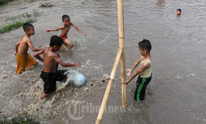 Anak-Anak Bermain Bola di Lapangan Terendam Air