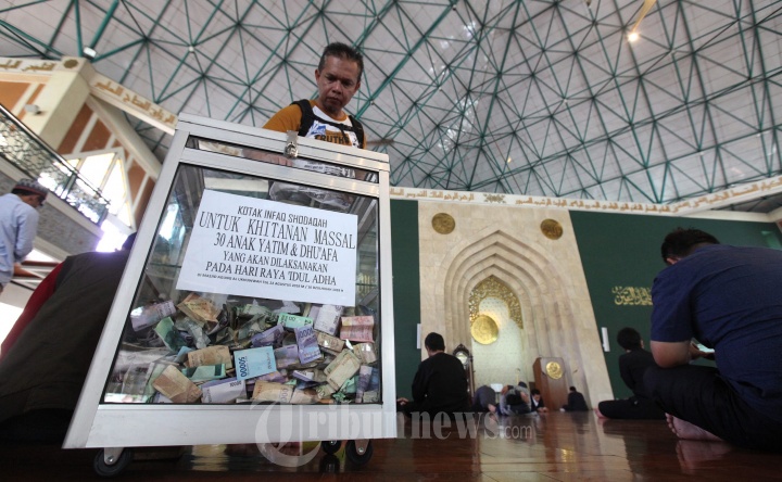 Jemaah Memasukan Uang Infaq ke Kotak Amal