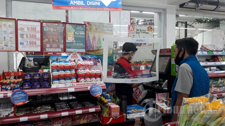 Kasir Layani Pembeli dengan Pelindung Plastik