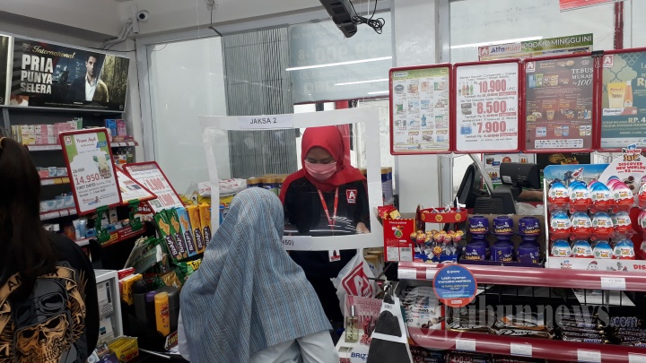 Kasir Layani Pembeli dengan Pelindung Plastik