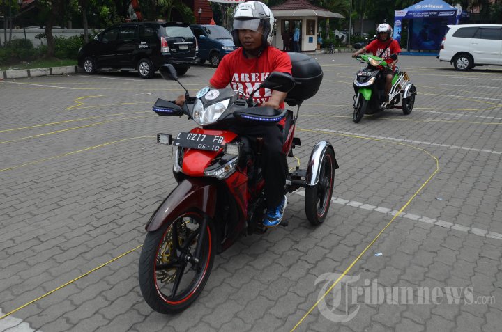 Peserta disabilitas saat beraksi adu ketangkasang dengan motor tiga roda dalam lomba slalom memperingati Hari Disabilitas Internasional yang digelar Badan Koordinasi Kegiatan Kesejahteraan Sosial (BK3S) Jatim di gedung BK3S, Jl Tenggilis, Surabaya, Minggu (7/12/2014). 