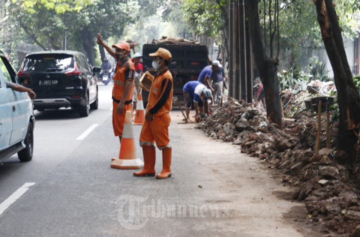 Pasukan PPSU membersihkan puing-puing bekas tembok roboh