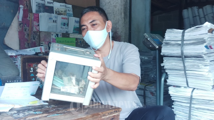 Warga Memasukan Sumbangan Uang Dikotak Amal di Warung