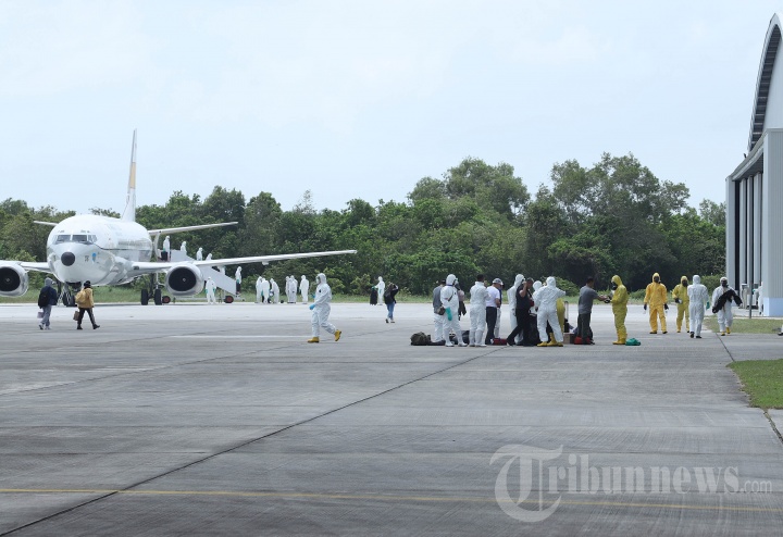 Petugas mengevakuasi WNI yang tiba dari Wuhan di lokasi observasi Hangar Lanud Raden Sajad, Natuna, Kepri, Minggu (2/2/2020). WNI yang sebelumnya transit terlebih dahulu di Batam tersebut dievakuasi dari Wuhan, China, akibat merebaknya wabah Virus Corona. 