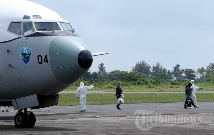 Petugas mengevakuasi WNI yang tiba dari Wuhan di lokasi observasi Hangar Lanud Raden Sajad, Natuna, Kepri, Minggu (2/2/2020). WNI yang sebelumnya transit terlebih dahulu di Batam tersebut dievakuasi dari Wuhan, China, akibat merebaknya wabah Virus Corona. 