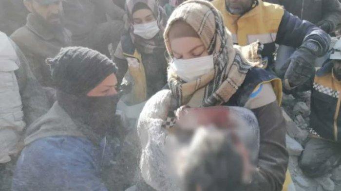 Salam al-Mahmoud, seorang sukarelawan kelompok pertahanan sipil White Helmets, memegang jenazah seorang anak laki-laki yang tewas di bawah reruntuhan di Bisinya, di barat laut Suriah