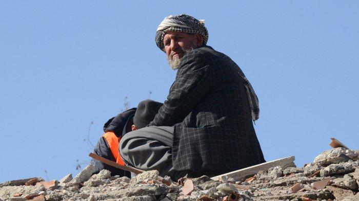 Seorang kerabat korban duduk di atas bangunan yang runtuh di Adiyaman, pada 9 Februari 2023, tiga hari setelah gempa berkekuatan 7,8 melanda Turki tenggara. Korban tewas akibat gempa besar yang melanda Turki dan Suriah naik menjadi lebih dari 17.100 pada 9 Februari, karena harapan untuk menemukan korban yang selamat terjebak di bawah puing-puing dalam cuaca yang sangat dingin memudar.