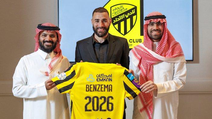 Dalam rilis gambar selebaran oleh Liga Pro Saudi pada 6 Juni 2023, pemain sepak bola Prancis Karim Benzema memegang kaus klub Al-Ittihad Arab Saudi saat ia berpose untuk foto diapit oleh anggota Al-Ittihad, di Madrid. Pemenang Ballon d'Or Real Madrid Karim Benzema akan bergabung dengan Cristiano Ronaldo di Arab Saudi setelah menandatangani kontrak tiga tahun dengan Al-Ittihad, klub yang berbasis di Jeddah mengkonfirmasi pada 6 Juni. jorge ferrari / Liga Pro Saudi /