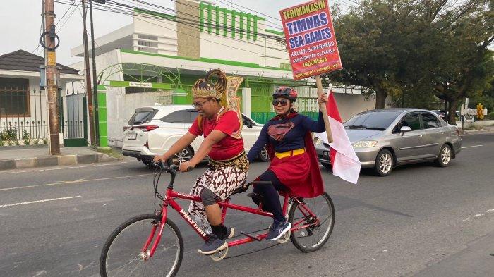 Pasutri berkostum superhero Gatotkaca dan Supergirl memenuhi nazar bersepeda atau gowes dengan jarak tempuh 20 KM dari Sukoharjo ke Solo setelah timnas Indonesia U-22 meraih emas SEA Games 2023, Jumat, 19 Mei 2023.