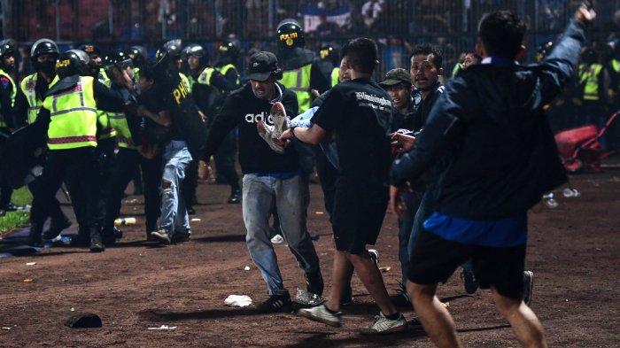 Dalam gambar yang diambil pada 1 Oktober 2022 ini, sekelompok orang menggendong seorang pria usai pertandingan sepak bola antara Arema FC dan Persebaya Surabaya di Stadion Kanjuruhan Malang, Jawa Timur. Stadion di Indonesia, tempat 135 orang tewas pada Oktober 2022 dalam salah satu tragedi terburuk sepak bola, masih kosong namun masih utuh, meskipun pemerintah berjanji untuk menghancurkannya dan membangun kembali stadion yang lebih aman.
