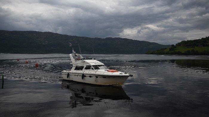 Wisatawan menaiki kapal 'Nessie Hunter' di Loch Ness di Dataran Tinggi Skotlandia pada 10 Juni 2018. Pencarian terbesar Monster Loch Ness dalam lima dekade berlangsung di Dataran Tinggi Skotlandia pada 26 Agustus 2023, ketika para peneliti dan penggemar dari seluruh dunia menantang hujan deras untuk mencoba melacak Nessie yang sulit ditangkap.