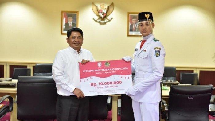 Direktur Jenderal Pendidikan Islam Kemenag, Muhammad Ali Ramdhani, memberikan bonus kepada Muhammad Adzan (17), siswa madrasah pertama yang menjadi anggota Pasukan Pengibar Bendera Pusaka (Paskibaraka) tahun 2020 dari unsur Madrasah, di kantor Kemenag RI, Selasa, (18/8/2020), didampingi Deputi Pengembangan Pemuda Kementerian Pemuda dan Olahraga, Asrorun Ni'am Sholeh.