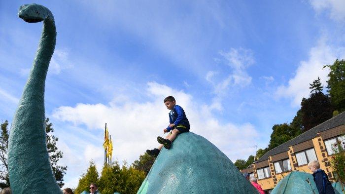 Anak-anak bermain di patung monster Loch Ness di Nessieland di Drumnadrochit di Dataran Tinggi Skotlandia pada 27 Agustus 2023. Pencarian terbesar Monster Loch Ness dalam lima dekade sedang berlangsung di Dataran Tinggi Skotlandia, saat para peneliti dan penggemar dari seluruh dunia berani melempari hujan untuk mencoba melacak Nessie yang sulit ditangkap. Ekspedisi tersebut mengerahkan drone dengan pemindai termal, perahu dengan kamera inframerah, dan hidrofon bawah air untuk mencoba mengungkap misteri yang telah memikat dunia selama beberapa generasi.