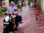 warga-melintas-di-genangan-air-banjir-berwarna-merah.jpg