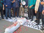mahasiswa-melakukan-aksi-tabur-bunga-di-atas-replika-pocong.jpg